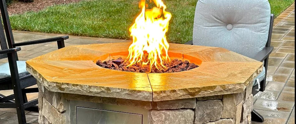 A burning fire pit in Durham, NC, with cushion seating.