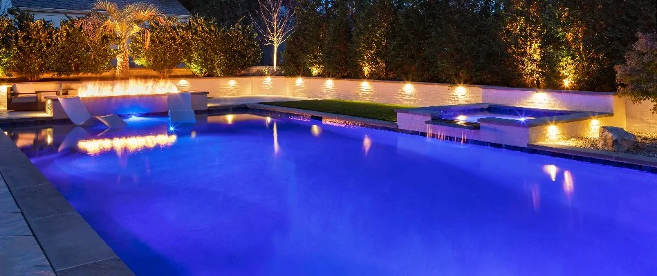 Clean pool in Cary, NC, with outdoor lighting and trees.