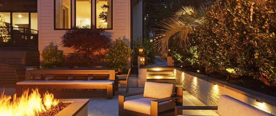 Fire pit with chairs in Raleigh, NC, surrounded by green shrubs.