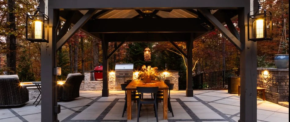 A patio with an outdoor kitchen and table under a pavilion in Cary, NC.