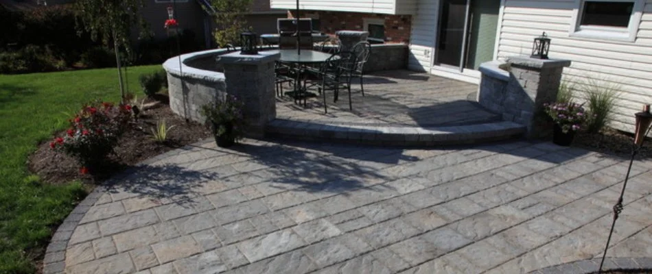 Paver patio with a seating wall beside a lawn in Cary, NC.