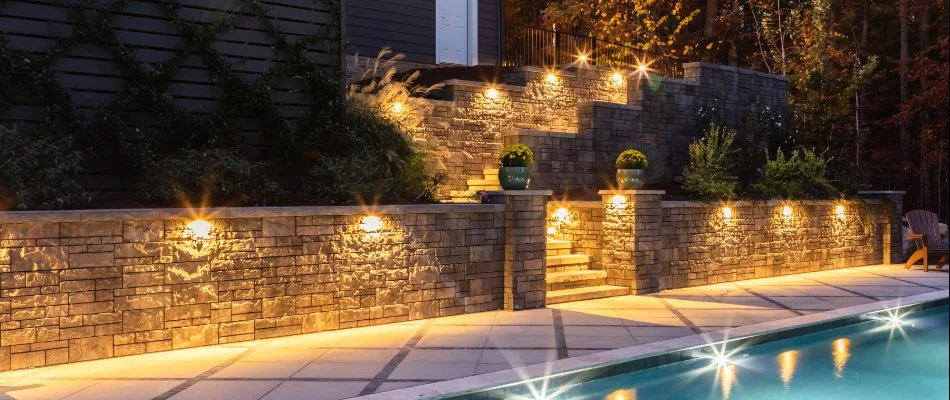 Retaining wall in Cary, NC, with plants and outdoor lighting by a pool.